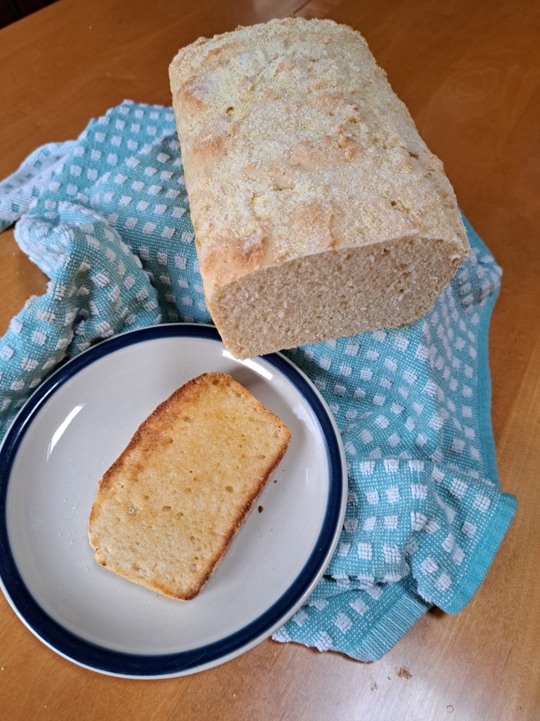English Muffin Bread sliced and sitting on a plate with checkered kitchen towel
